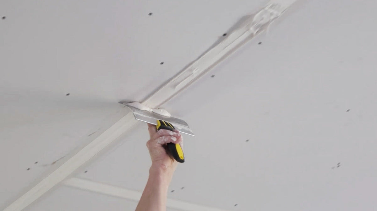 A drywaller coating tape using a taping knife